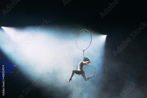 Aerial acrobat in the ring. A young girl performs the acrobatic elements in the air ring.