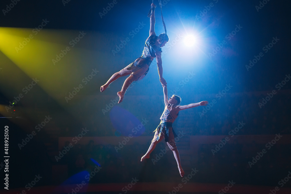 Circus actress acrobat performance. Two boys perform acrobatic elements in the air. Circus actress acrobat performance. Two boys perform acrobatic elements in the air.