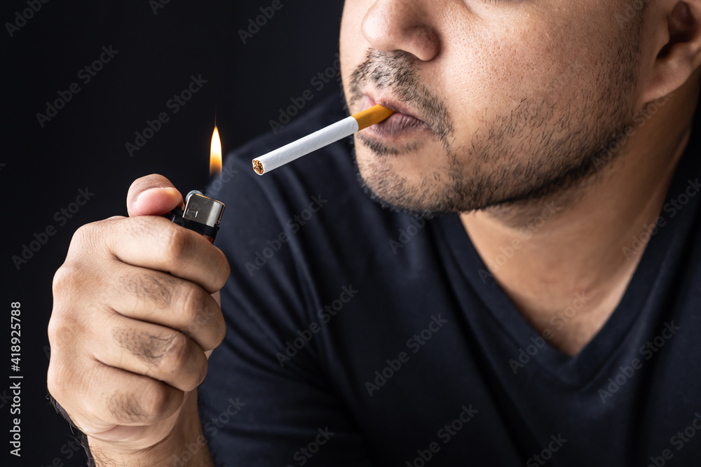 Obraz premium A young man with a cigarette He is going to smoke He lit the cigarette lighter with a lighter, and the smoke floated around.