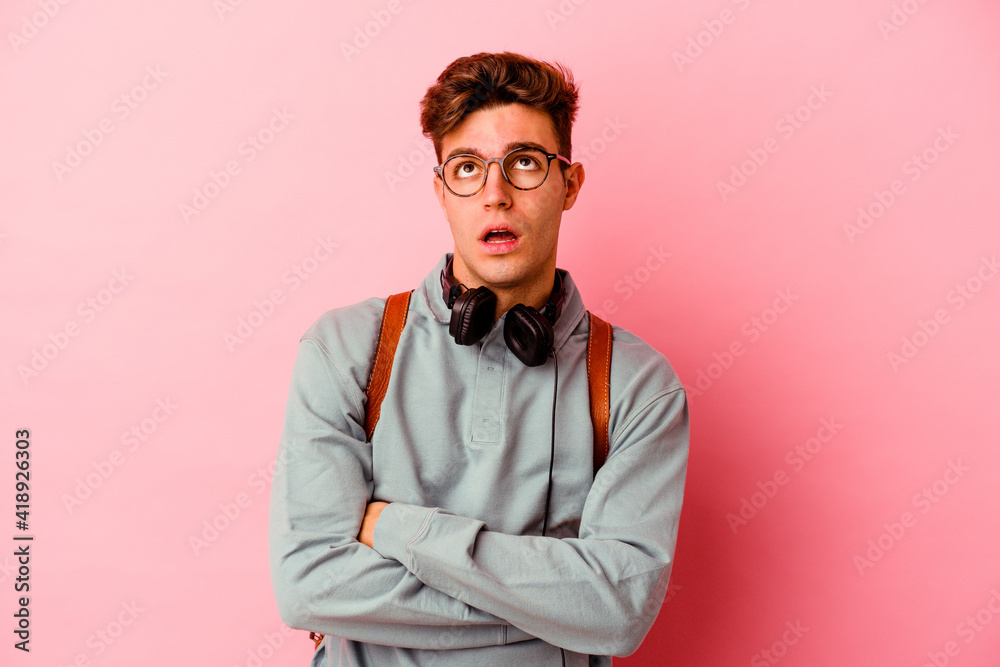 Young student man isolated on pink background tired of a repetitive task. Young student man isolated on pink background tired of a repetitive task.