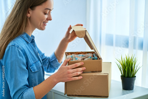 Happy joyful casual young attractive smiling woman received a parcels from internet shop photo