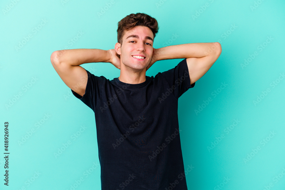 Young caucasian man isolated on blue background feeling confident, with hands behind the head. Young caucasian man isolated on blue background feeling confident, with hands behind the head.