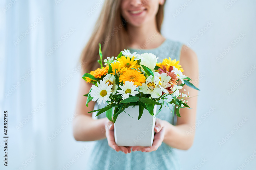 Woman holds decorative colorful bright fresh flower hat box at spring time