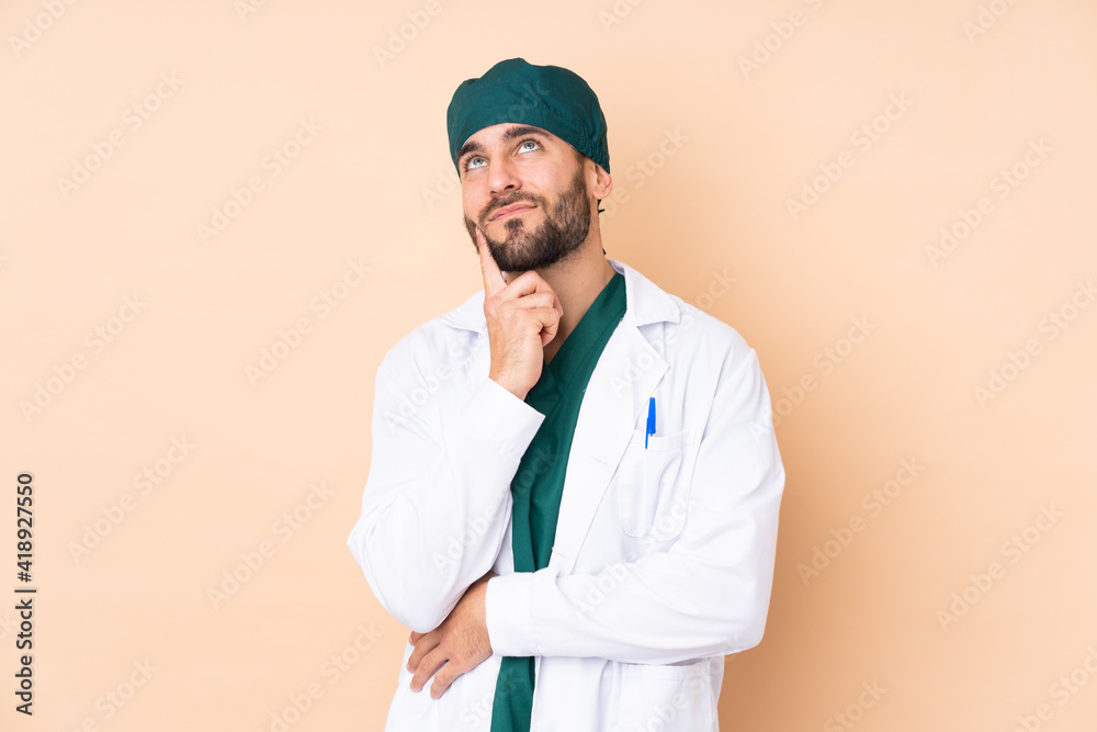 Surgeon man isolated on beige background thinking an idea Surgeon man isolated on beige background thinking an idea