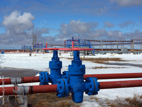 Gas transmission system against the backdrop of the snow tundra and last year's grass. Red-blue vents. Blue sky with clouds