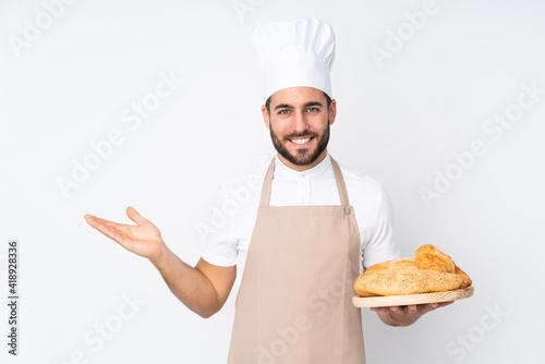 Fotografia Male baker holding a table with several breads isolated on white background hold