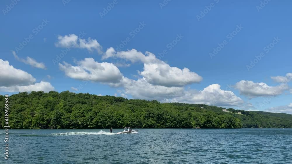 Wake Surfing on a Lake Near a Forest on a Sunny Day Wake Surfing on a Lake Near a Forest on a Sunny Day