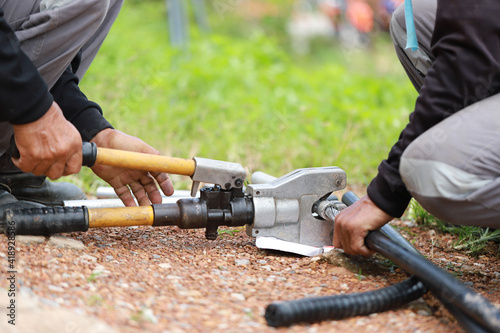 Hand of electrician repairman worker cutting cable. Industrial mounting concept. Professional safety job with personal protective equipment. 