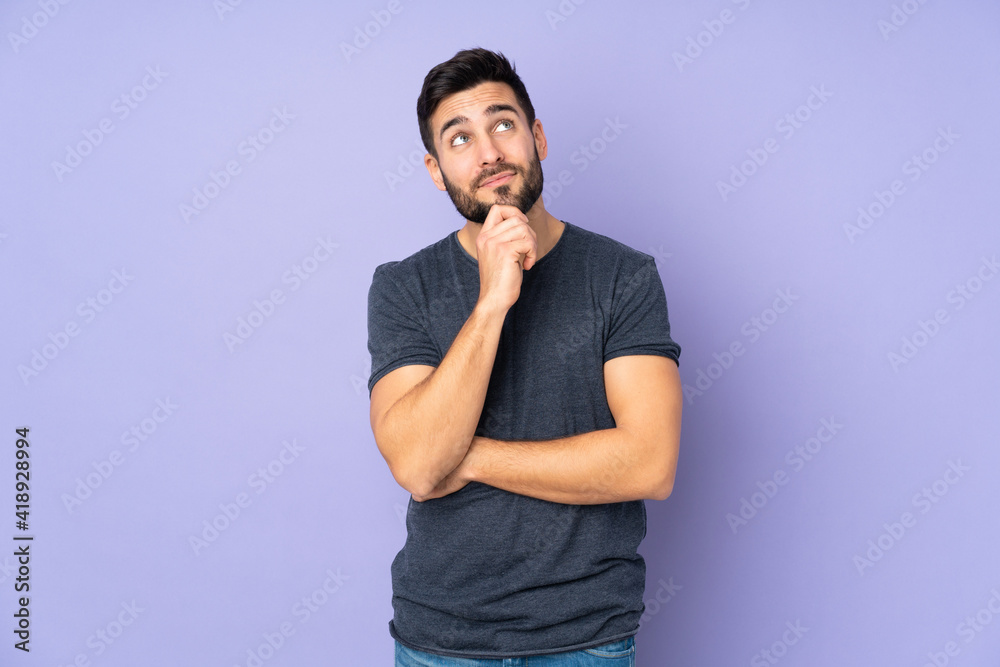 Caucasian handsome man and looking up over isolated purple background Caucasian handsome man and looking up over isolated purple background
