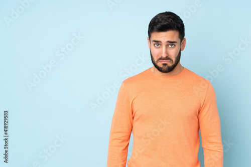 Caucasian handsome man with sad expression over isolated blue background