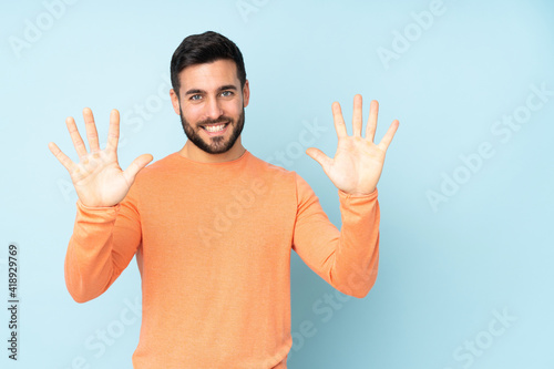 Caucasian handsome man counting ten with fingers over isolated blue background