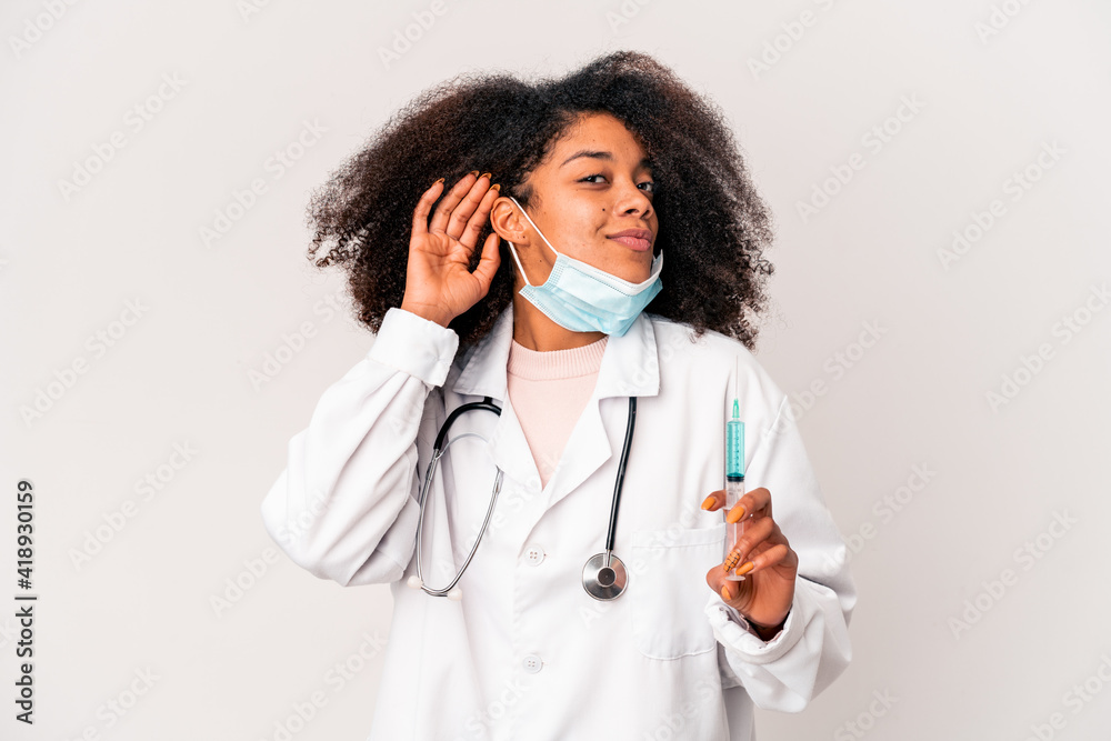 Young african american curly doctor woman holding a syringe trying to listening a gossip. Young african american curly doctor woman holding a syringe trying to listening a gossip.