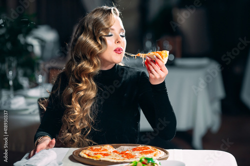 Young beautiful girl alone eating pizza in a restaurant.