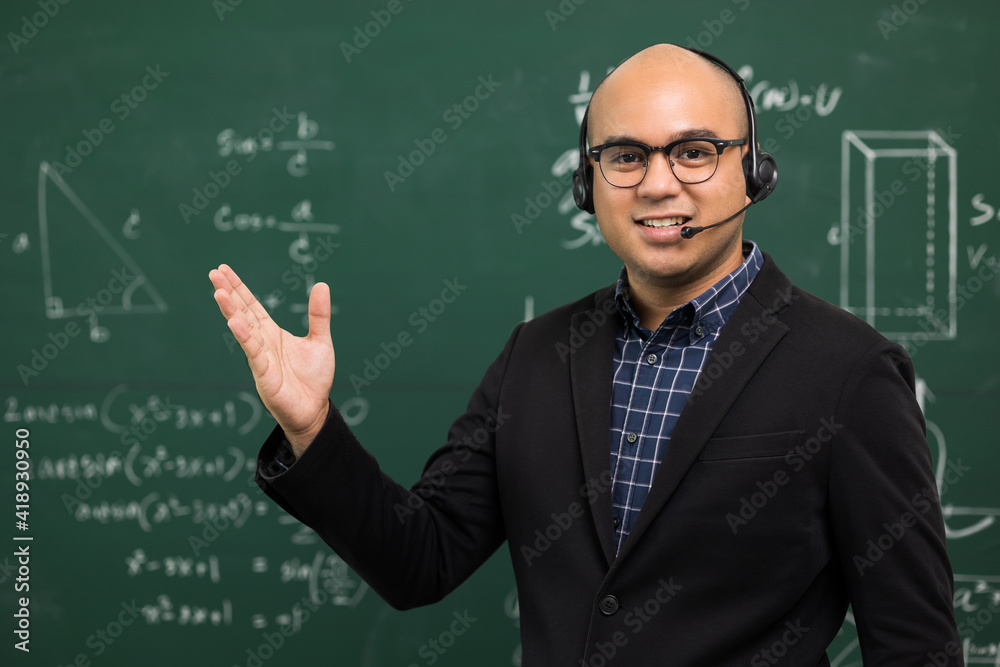 Young asian teacher man teaching video conference with student. Male Indian teacher training the mathematics in classroom from online course. He wearing small talk headset. Young asian teacher man teaching video conference with student. Male Indian teacher training the mathematics in classroom from online course. He wearing small talk headset.