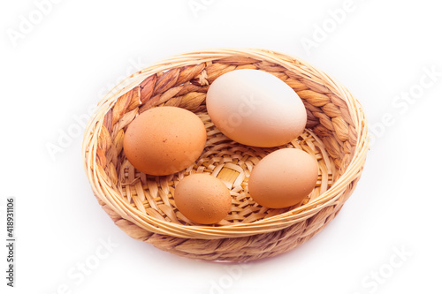 Wallpaper Mural eggs - four chicken eggs of different sizes in a small wicker basket, isolated on white background Torontodigital.ca