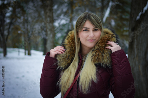 Beautiful blonde girl walking in the park on snowy winters day.