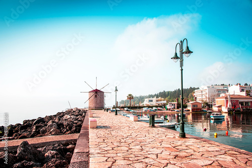 Obraz na płótnie Charming seafront view with stones, lanterns and old windmill on the coast of the Mon Repose area in Kerkira, capital of Corfu, Greece. Amazing places. Popular tourist atraction. w salonie