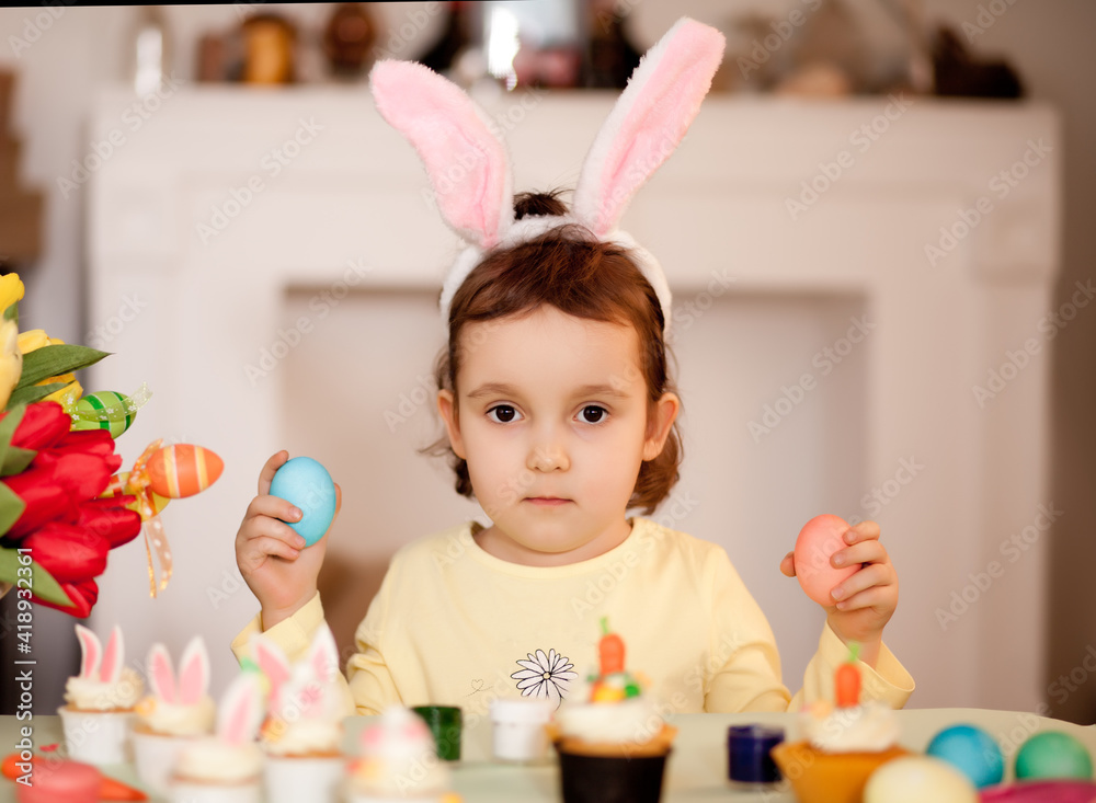 Funny girl child wearing bunny ears and with Easter egg in hand at home. Funny girl child wearing bunny ears and with Easter egg in hand at home.