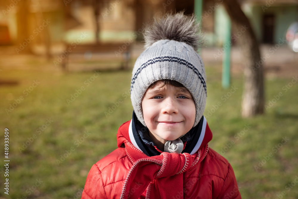 Portrait of a young boy in warm clothes in early spring, he is gaining strength after a long winter and basking in the sun, he needs vitamin D