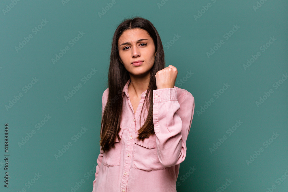 Young Indian woman isolated on blue background showing fist to camera, aggressive facial expression. Young Indian woman isolated on blue background showing fist to camera, aggressive facial expression.