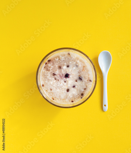 top view of bowl of oatmeal on yellow background, minimal design, healthy breakfast of instant porridge with freeze-dried berries