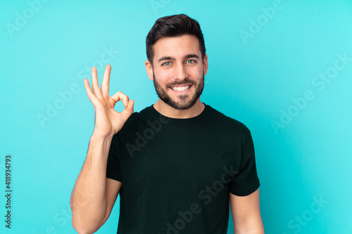 Caucasian handsome man isolated on blue background showing ok sign with fingers photo