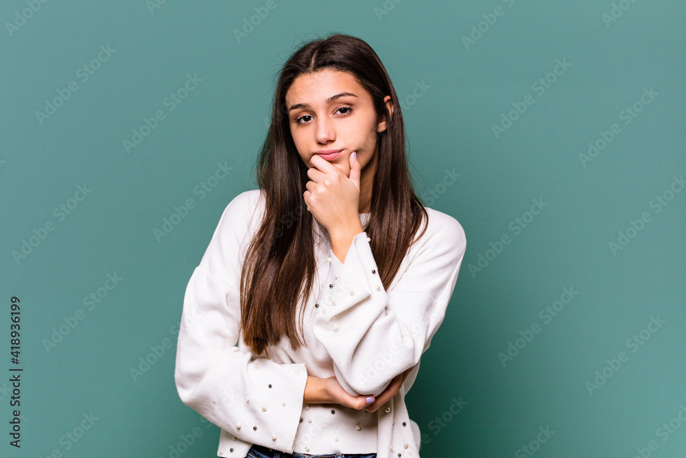 Young Indian woman isolated on blue background suspicious, uncertain, examining you. Young Indian woman isolated on blue background suspicious, uncertain, examining you.
