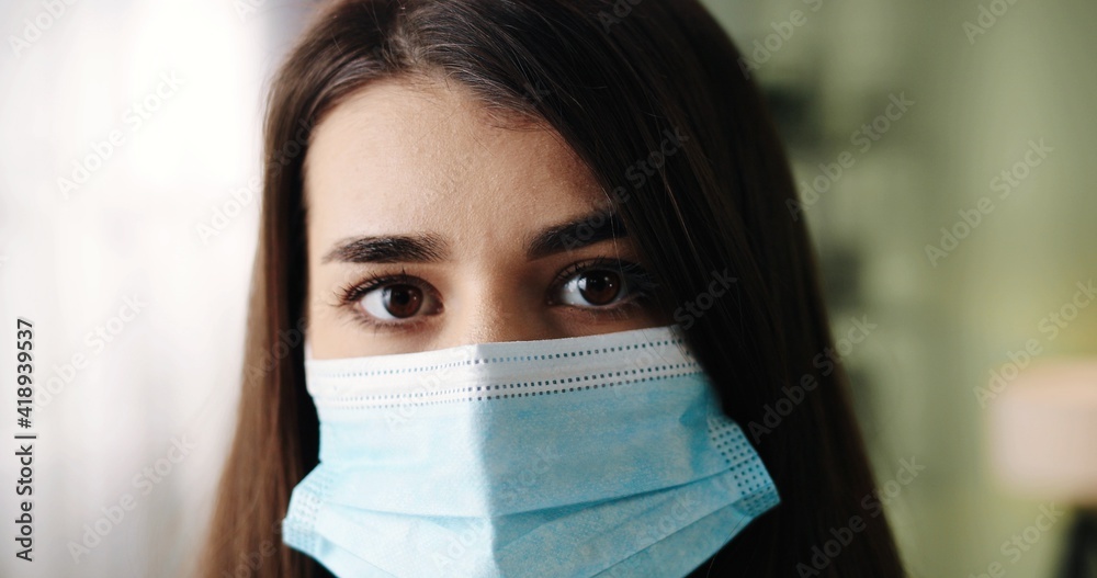 Close up of Caucasian beautiful young female enters the room and removing medical mask from face sitting down on couch at home with tired face. Quarantine coronavirus, healthcare concept Close up of Caucasian beautiful young female enters the room and removing medical mask from face sitting down on couch at home with tired face. Quarantine coronavirus, healthcare concept