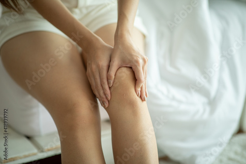 woman have a kneecap pain sitting on bed in bedroom after wake up feeling so illness Healthcare concept