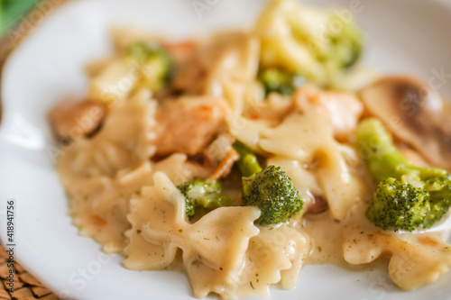 Homemade chicken penne with broccoli on a white plate side view. Close up.