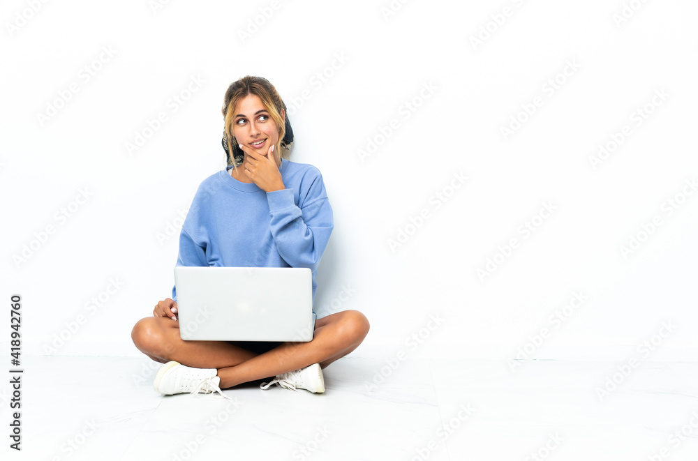 Young blonde Uruguayan girl with the laptop isolated on white background having doubts and with confuse face expression Young blonde Uruguayan girl with the laptop isolated on white background having doubts and with confuse face expression