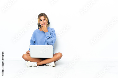 Young blonde Uruguayan girl with the laptop isolated on white background having doubts and with confuse face expression