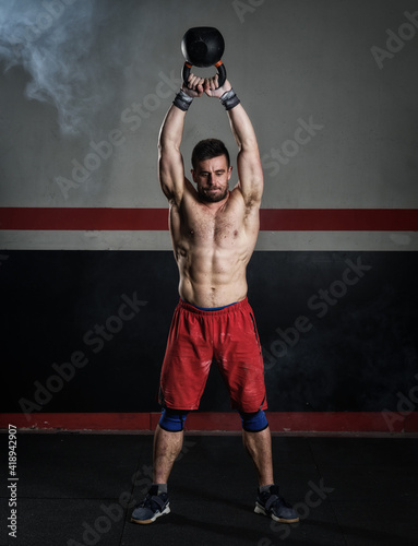 young man lifting heavy kettelbell

 photo