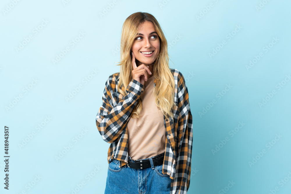 Young blonde Uruguayan isolated on blue background thinking an idea while looking up Young blonde Uruguayan isolated on blue background thinking an idea while looking up