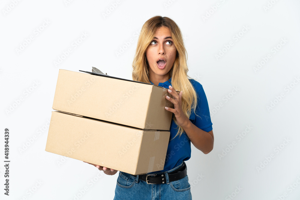Young blonde Uruguayan delivery woman isolated on white background looking up and with surprised expression Young blonde Uruguayan delivery woman isolated on white background looking up and with surprised expression