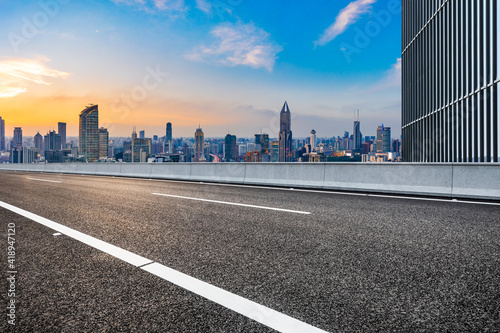 Empty asphalt road and city skyline with buildings at sunset in Shanghai.