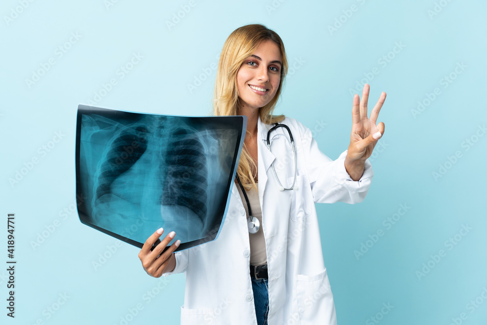 Young blonde Uruguayan doctor woman isolated on blue background happy and counting three with fingers Young blonde Uruguayan doctor woman isolated on blue background happy and counting three with fingers