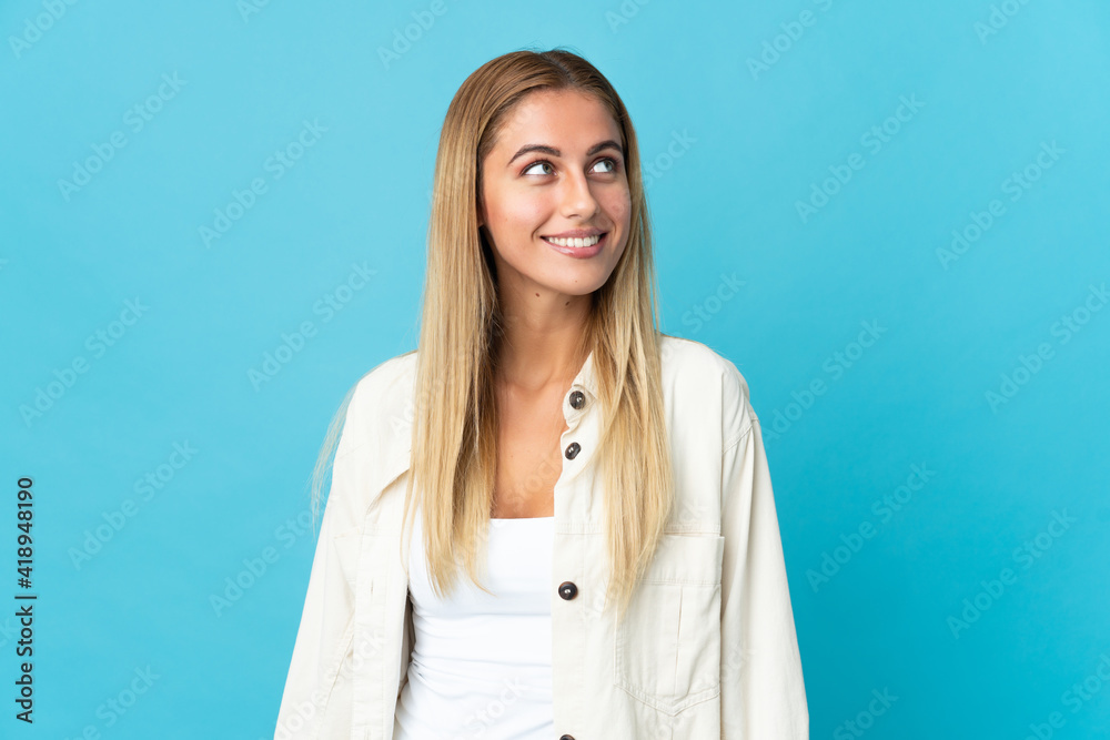 Young blonde woman isolated on blue background thinking an idea while looking up Young blonde woman isolated on blue background thinking an idea while looking up