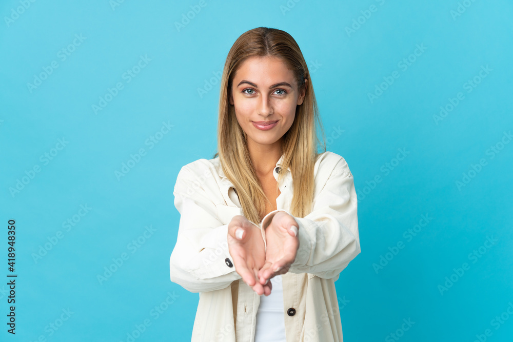 Young blonde woman isolated on blue background holding copyspace imaginary on the palm to insert an ad Young blonde woman isolated on blue background holding copyspace imaginary on the palm to insert an ad