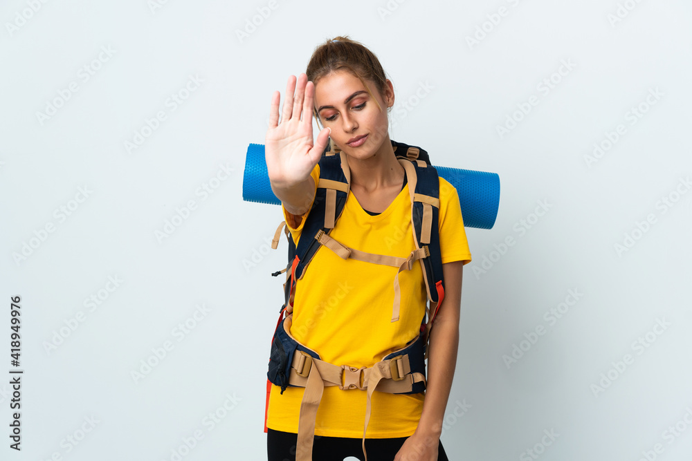 Young mountaineer woman with a big backpack isolated on white background making stop gesture and disappointed Young mountaineer woman with a big backpack isolated on white background making stop gesture and disappointed