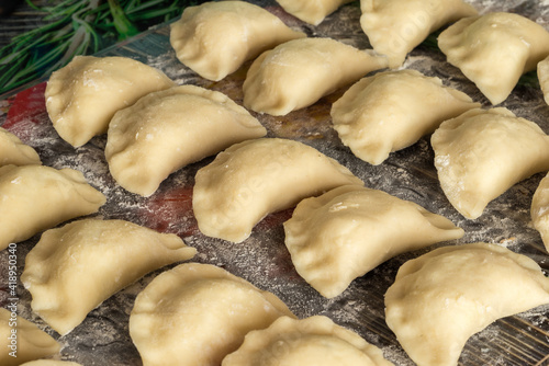 Dumplings before being boiled. Traditional Polish hand-made food. Polish pierogi arranged in rows close up photo