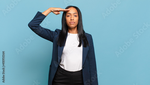 Bild auf Leinwand young black woman greeting the camera with a military salute in an act of honor and patriotism, showing respect