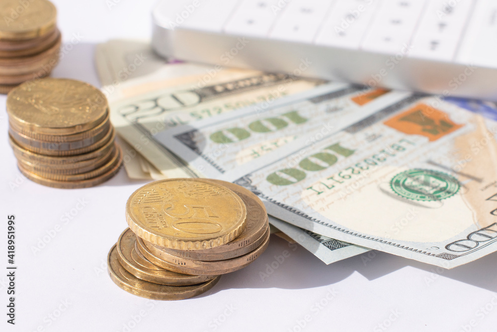 A calculator,stacks of coins and a bundle of 100 dollars on a white background A calculator,stacks of coins and a bundle of 100 dollars on a white background