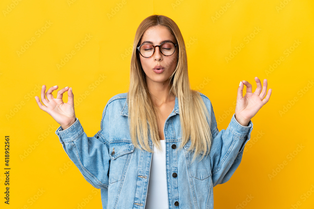Young blonde woman isolated on yellow background in zen pose Young blonde woman isolated on yellow background in zen pose