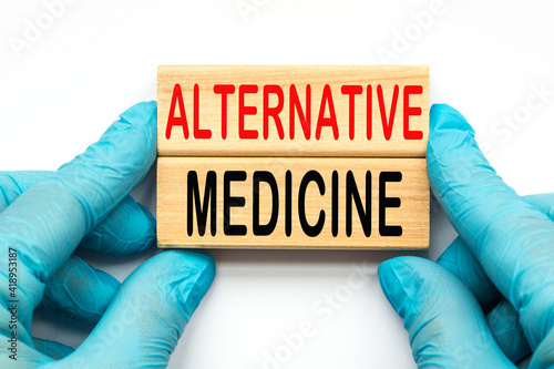 The doctor's hands show the word ALTERNATIVE MEDICINE . a gloved hand on a white background. Medical concept. the medicine