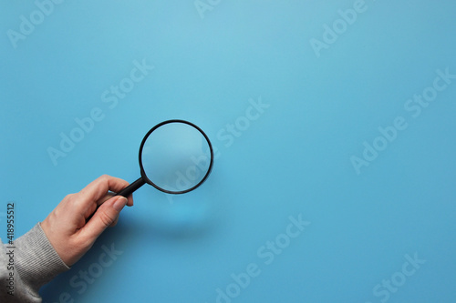 A man holds a magnifying glass in his hand. A symbol of finding something or revealing a secret