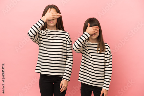 Little sisters girls isolated on pink background covering eyes by hands. Do not want to see something