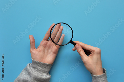 A person examines his hands under a magnifying glass. Fear of disease and infection. Protection and prevention of the disease