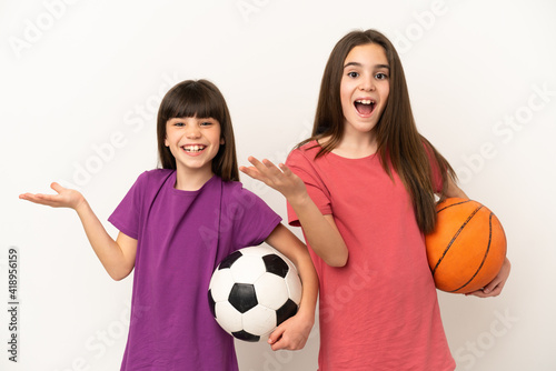 Little sisters playing football and basketball isolated on white background with surprise and shocked facial expression
