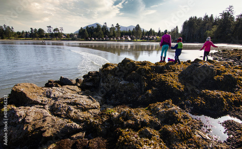 Children exploring at low tide while on vacation at a beach side cabin resort near Tofino British Columbia. photo